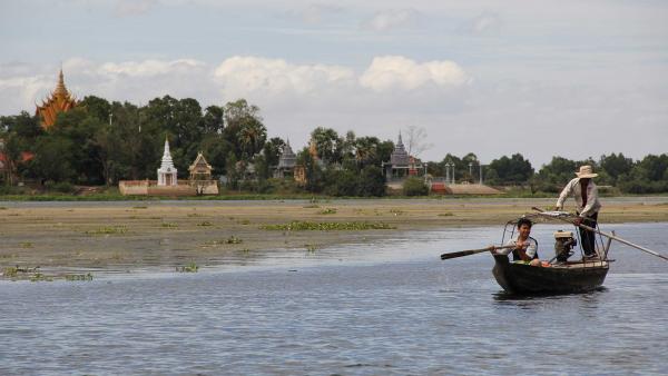 Des temples au loin et une pirogue sur le Mekong