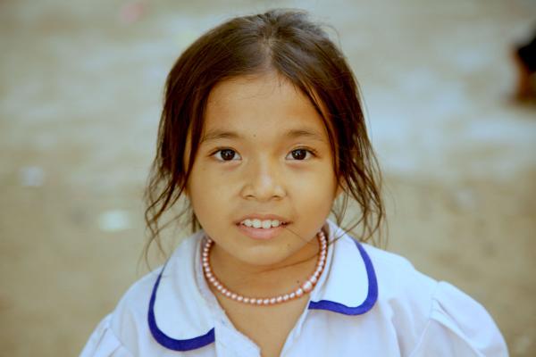 Une petite fille en uniforme scolaire regarde l'appareil photo