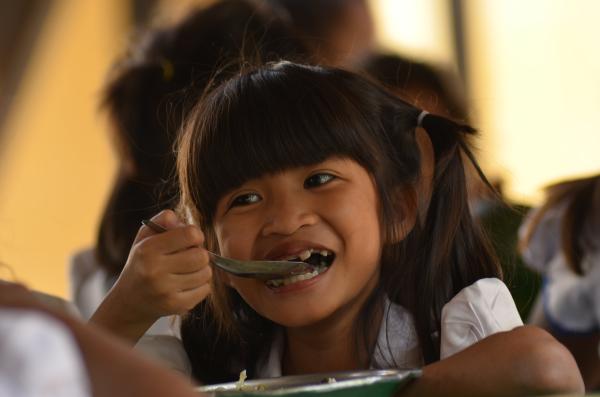Une petite fille en train de déjeuner à la cantine de PSE