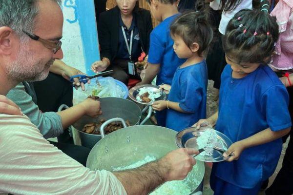 Un bénévole de PSE Hong Kong distribue des repas aux enfants des paillotes de PSE