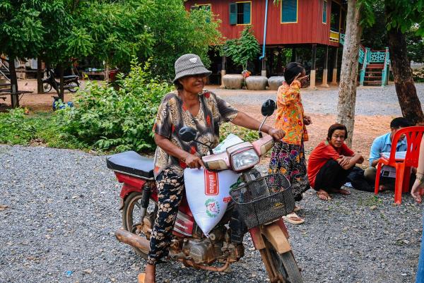 Une maman avec son sac de riz sur sa moto après une distribution de riz à Oudong