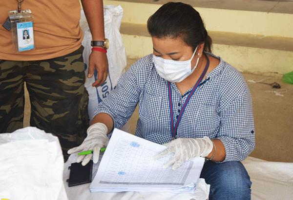 Une employée de PSE vérifie les listes pour la distribution de riz