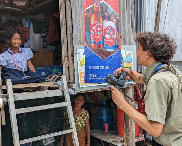 VuTheara dans un bidonville avec son appareil photo à la main, échange avec une petite fille en unif