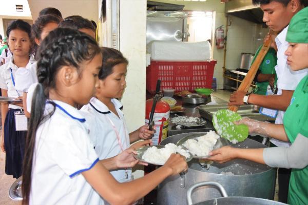 Deux petites filles se font servir leur repas à la cantine de Pour un Sourire d'Enfant