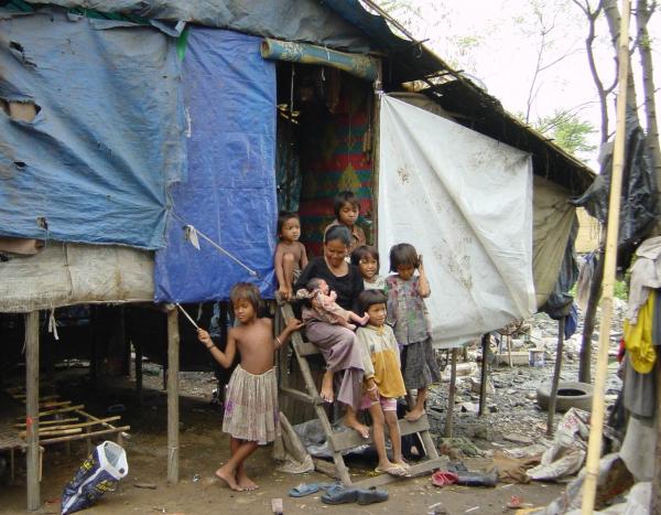 A family in front of their tin house in a community